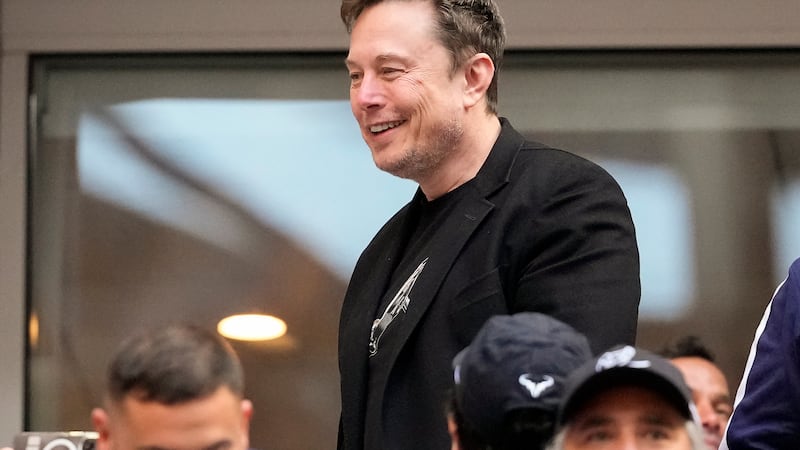 Elon Musk talks to other spectators while watching play between Jannik Sinner, of Italy, and...